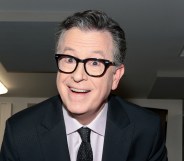 Stephen Colbert smiling at the camera in a suit