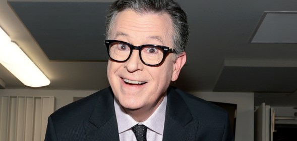 Stephen Colbert smiling at the camera in a suit