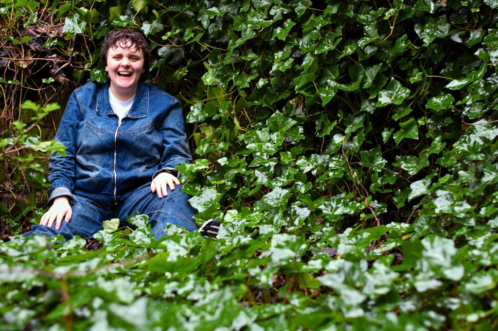 Eva Peroni: Jungled. Eva in blue denim trousers and jacket sat amongst ivy plants.
