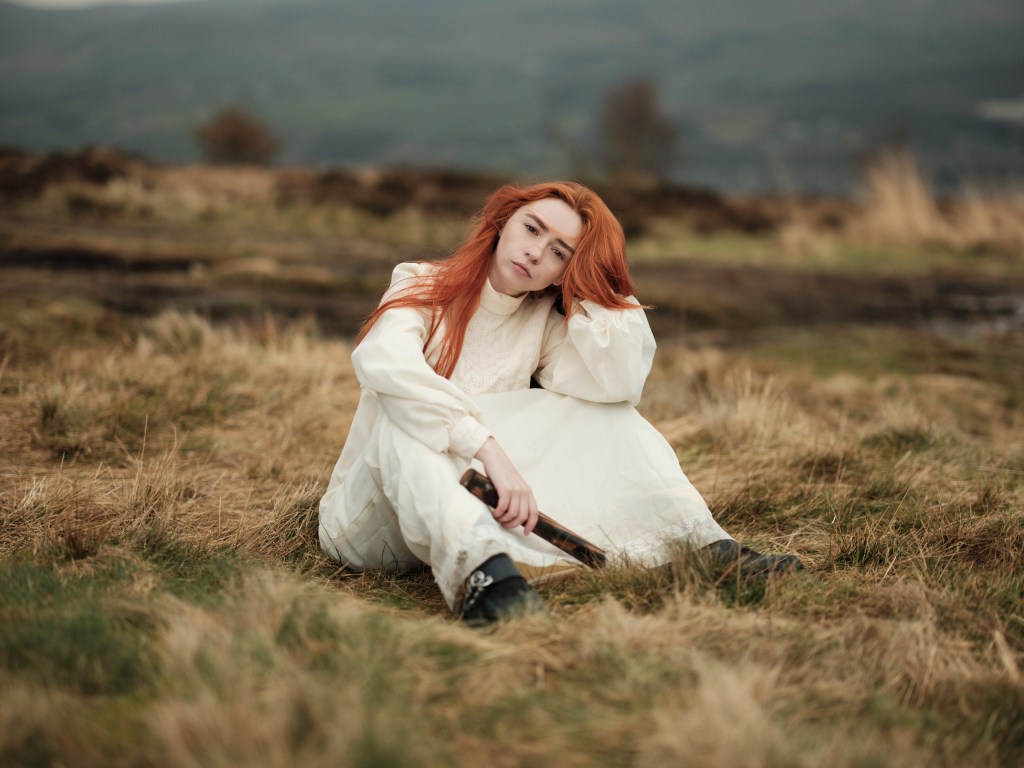 Hannah Platt: Cult Classic. A woman with red hair and a long, white dress in a field