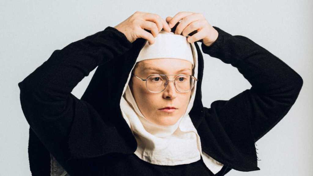 Scout Boxall: God's Favourite: a still of Scout putting on a nun outfit