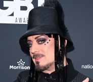 Boy George attends the British LGBT Awards 2026. He's wearing a black hat with fringe, three gemstones under his eye and a pistripe shirt