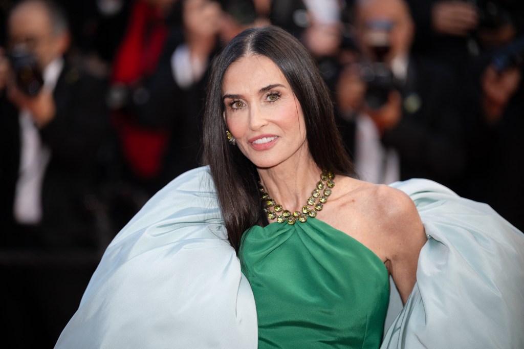 Demi Moore on a red carpet with a green dress and big grey shawl