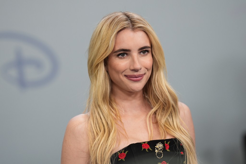 Emma Roberts posing in a black dress with red rose print