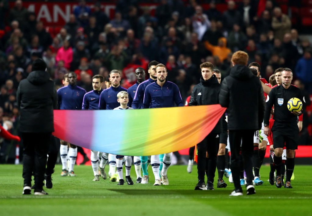 Harry Kane walking onto the pitch with a rainbow banner in front of him