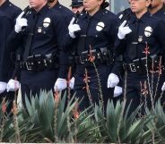 With black ribbons across their badge and holding a gun, police recruits attend their graduation ceremony at LAPD Headquarters