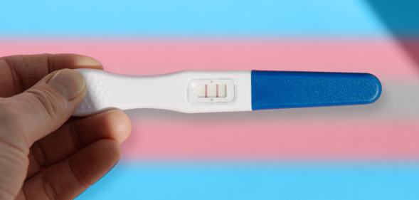 person holding a pregnancy test over trans flag colours