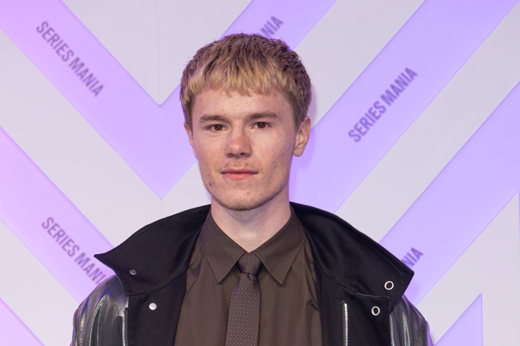 Edvin Ryding on the red carpet in a black leather jacket and brown shirt and tie.
