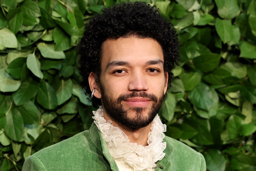 Justice Smith in a green suit with a ruffle neck shirt