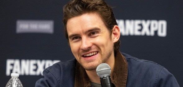 Actor Michael Johnston during the FanExpo Chicago. He's smiling in a dark navy jacket with dark brown cordoroy collar.