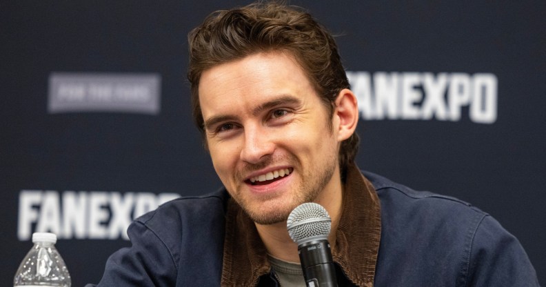 Actor Michael Johnston during the FanExpo Chicago. He's smiling in a dark navy jacket with dark brown cordoroy collar.