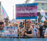 Trans people and allies at Trans+ Pride in London, with one person holding a sign criticising the EHRC.