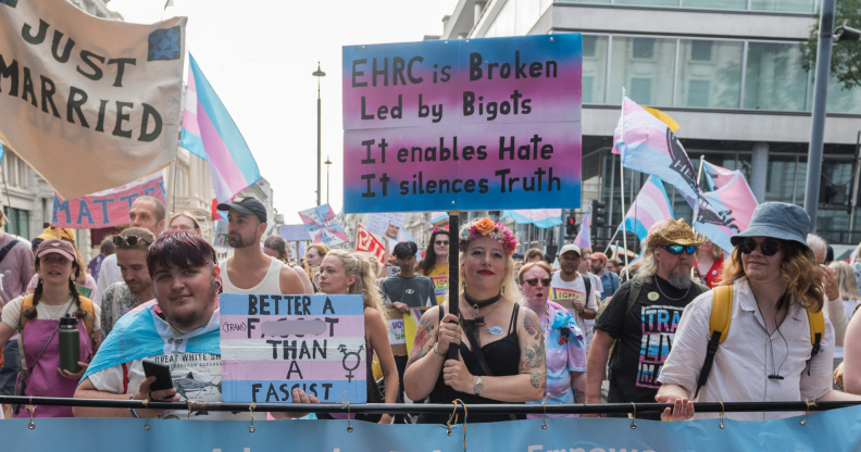 Trans people and allies at Trans+ Pride in London, with one person holding a sign criticising the EHRC.