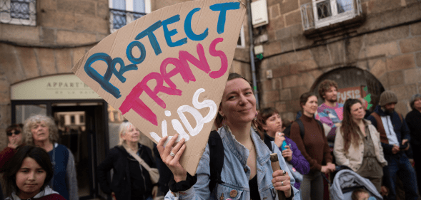 Someone holding a sign reading 'Protect trans kids'