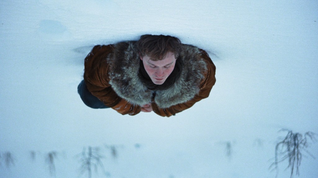 A Long Winter: A man lying in the snow, the image upside down.