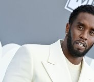 Music mogul Sean "Diddy" Combs wears a white shirt and matching suit while posing for a picture at an event