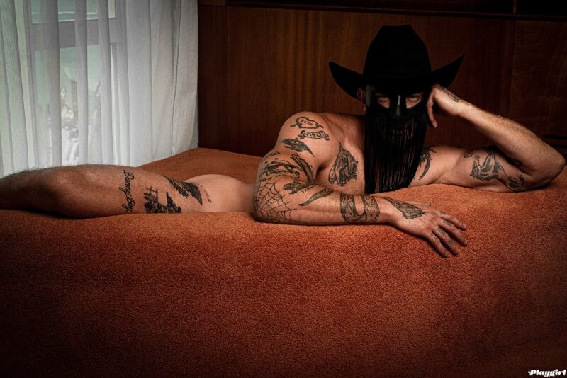 Orville Peck naked but covered by orange sofa
