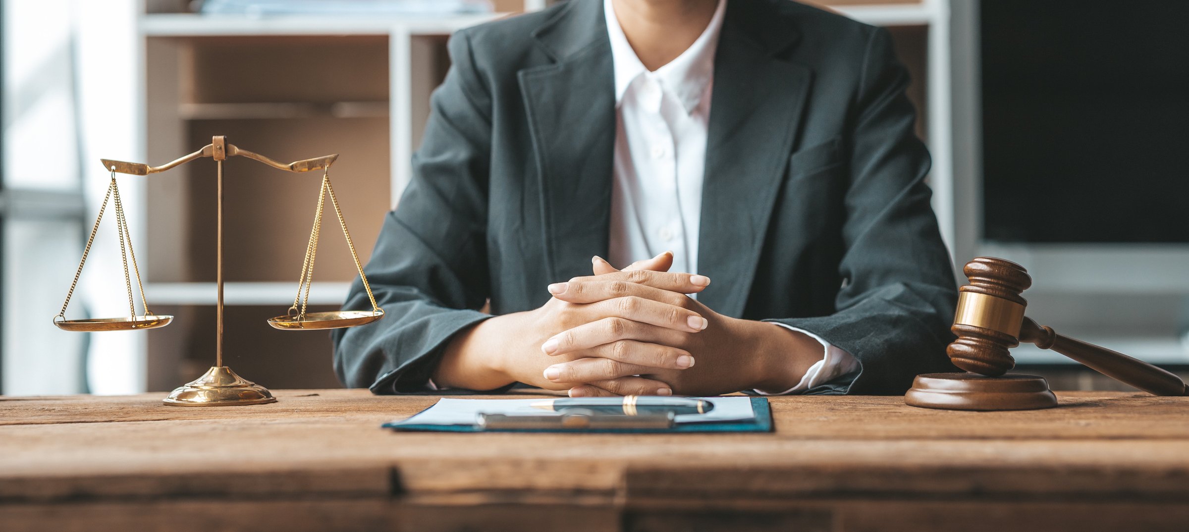 Person sitting at a desk with scales of justice and a gavel