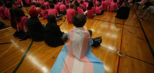 A student wears a trans flag during an assembly