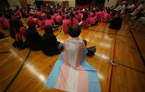 A student wears a trans flag during an assembly