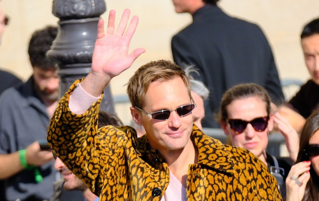 Alexander Skarsgård in printed jacket and mini sunglasses, waving